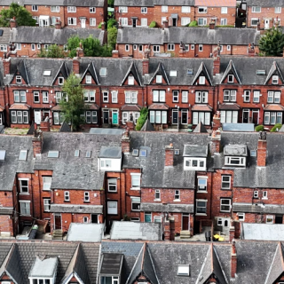Aerial view of dense rows of red-brick terraced houses with chimneys, rooftops, and narrow streets in a residential neighbourhood by David Pickup from https://www.pexels.com/photo/an-aerial-view-of-a-row-of-houses-in-a-city-27874104/