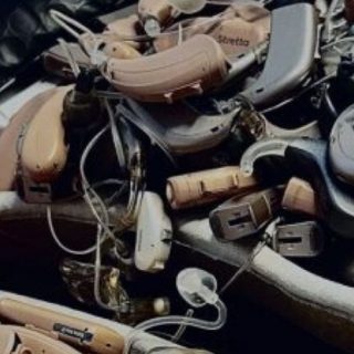Collection of hearing aids and accessories in a tray during research or recycling project.