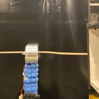 Acoustic test chamber with sound-absorbing foam walls, central experimental apparatus, and enclosed measurement equipment.