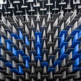 Acoustic test chamber lined with grey sound-absorbing foam wedges, featuring a central pattern of blue panels.